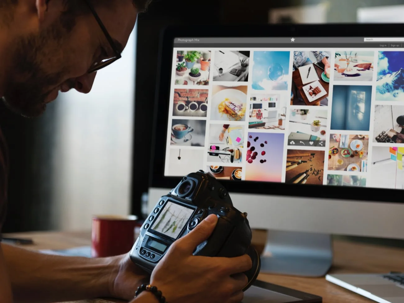 Photographer with a camera beside a computer displaying a website