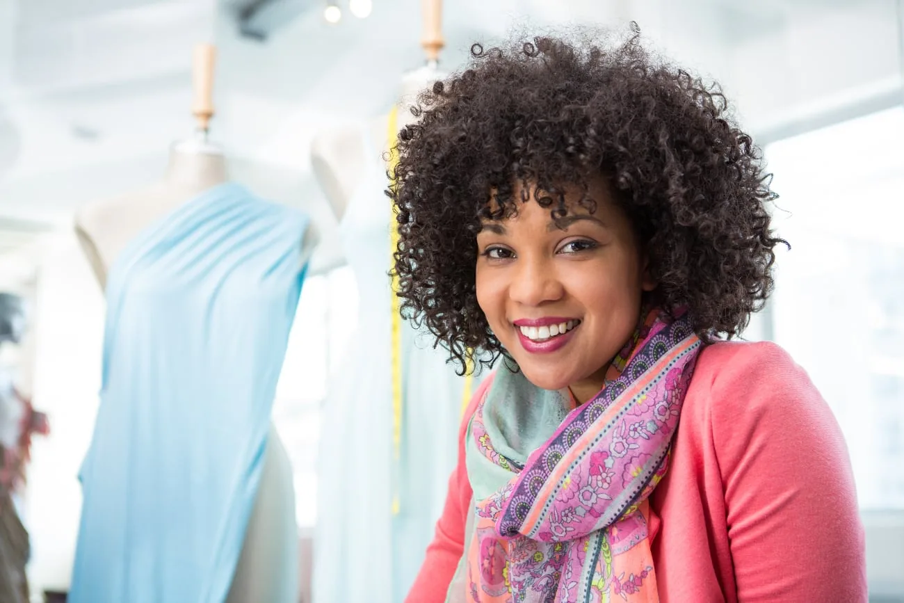 Smiling woman with curly hair and scarf in a clothing store