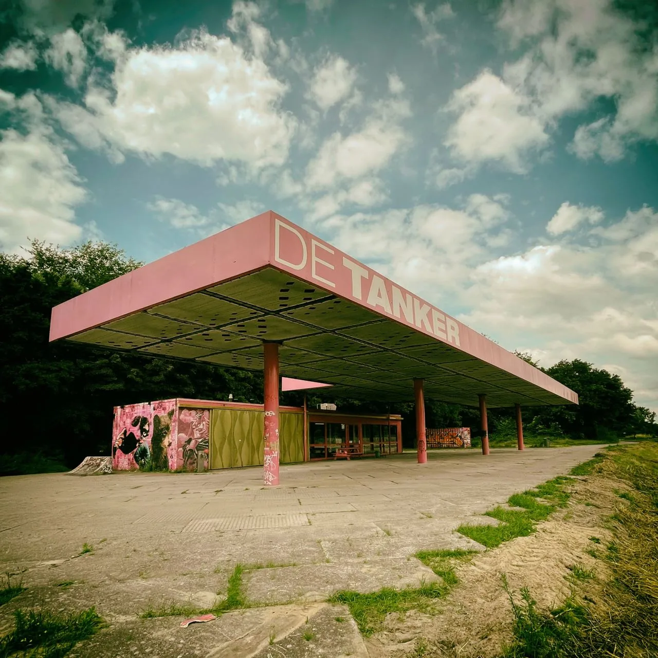 Abandoned pink gas station under a cloudy sky
