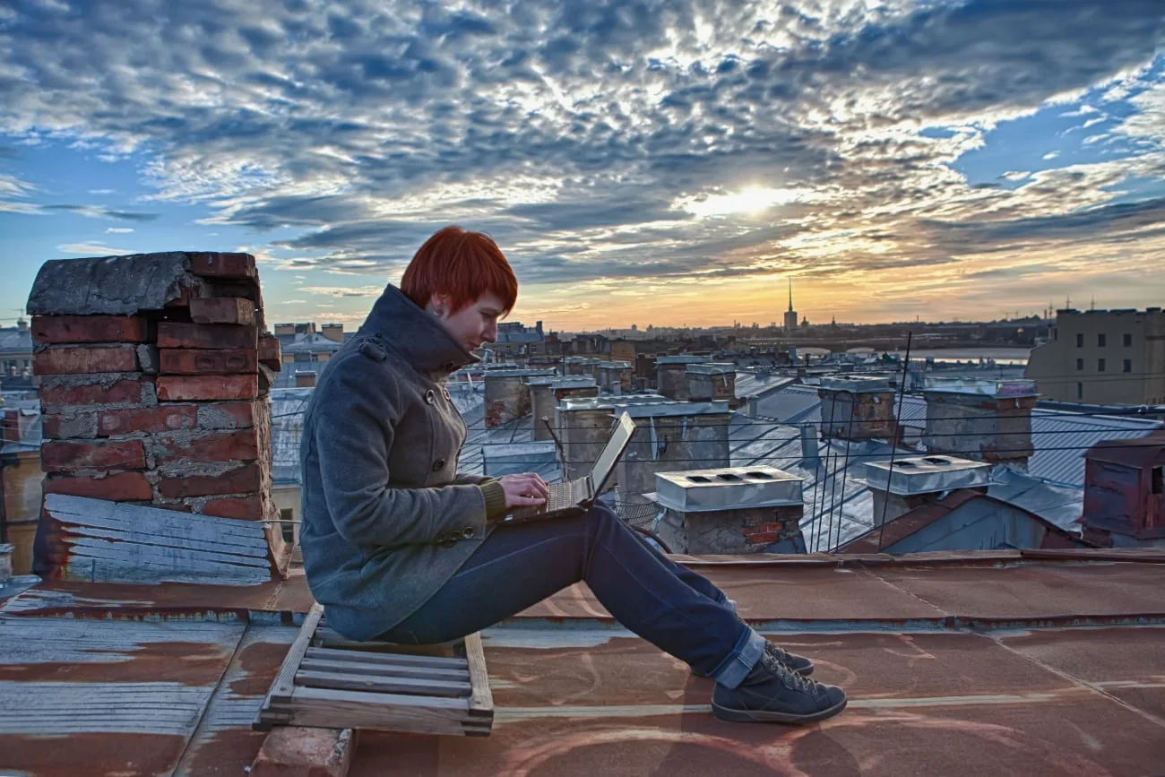 Roodharige vrouw werkt met een smartphone op een dak