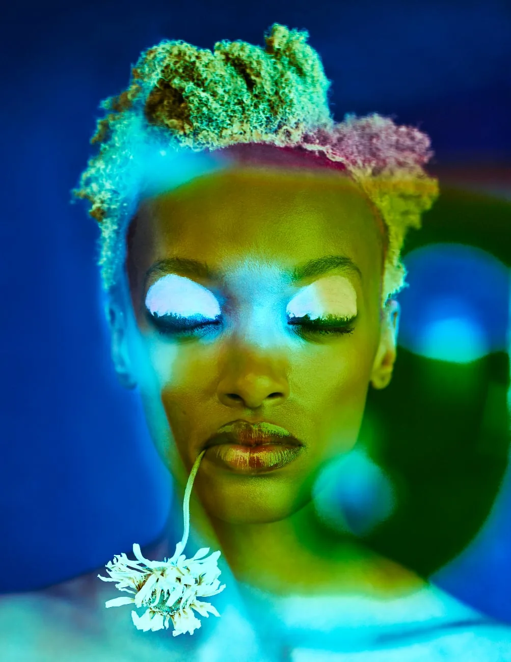 Portretfoto met fel blauwgroen licht van een model met gesloten ogen en een bloem bij de mond.