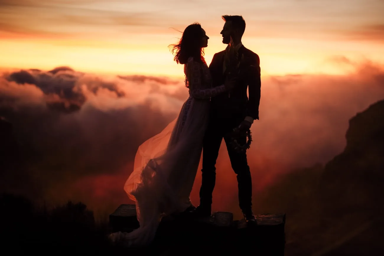 Silhouette of a wedding couple at sunset above the clouds
