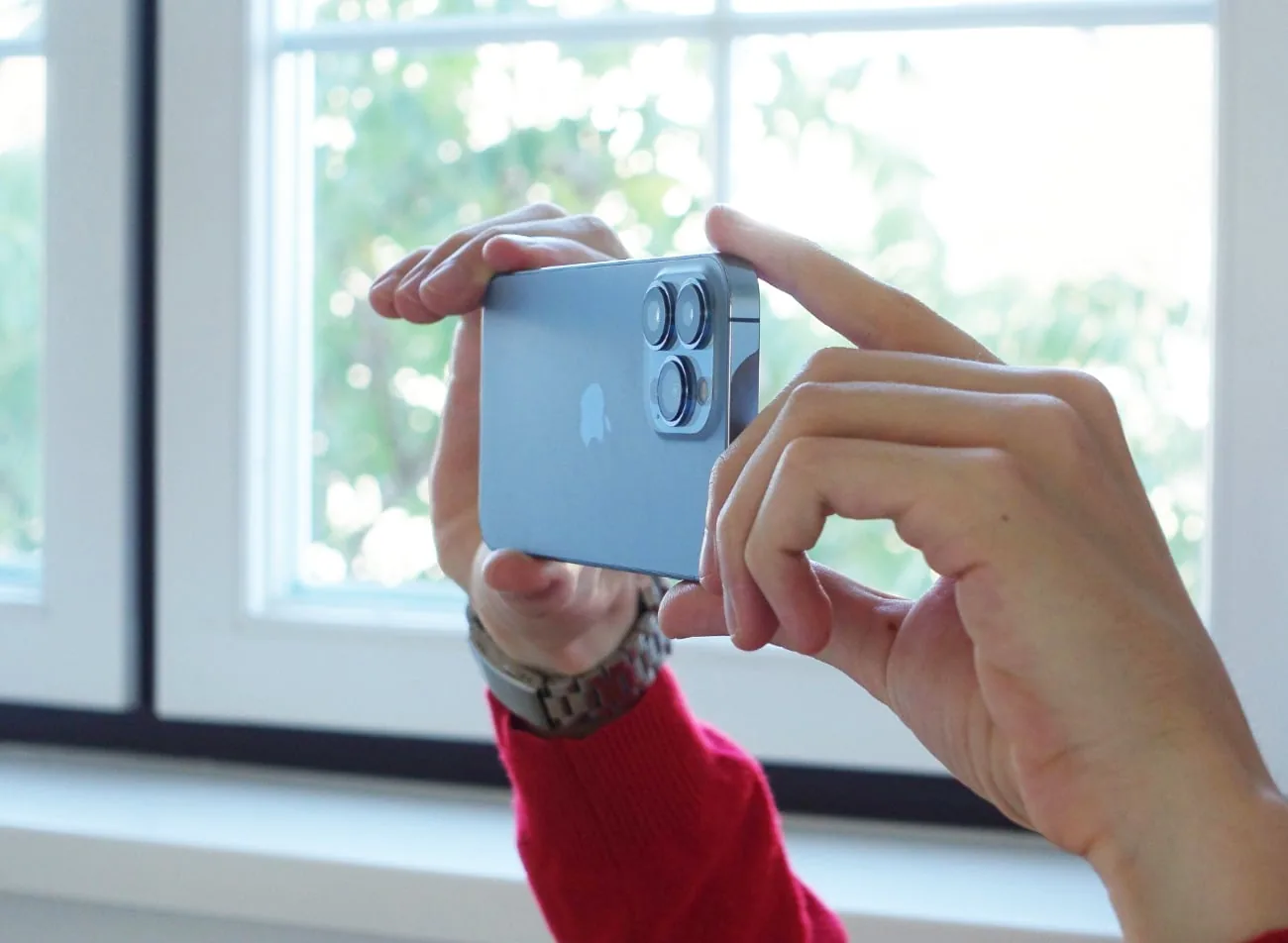 hands hold smartphone to take photo with window as background