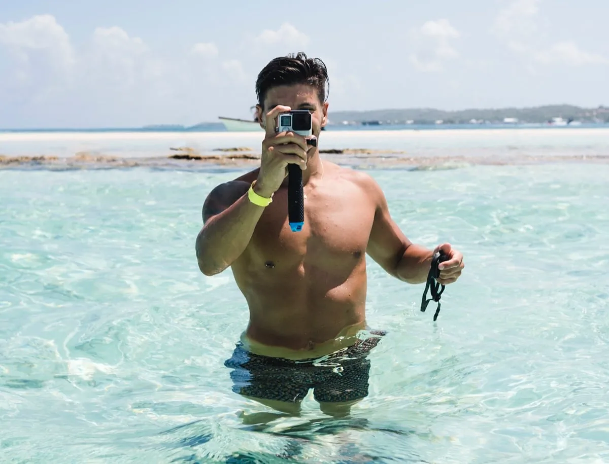 man staat in zee met GoPro in hand