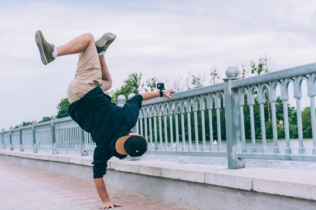 man doet breakdance bij brug met GoPro aan arm