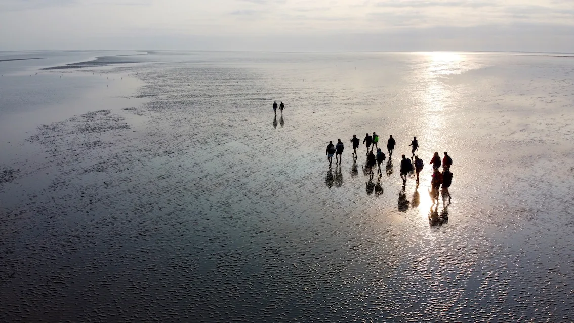 groepje fotografen van bovenaf gefotografeerd op wadden tijdens workshop bij ondergaande zon