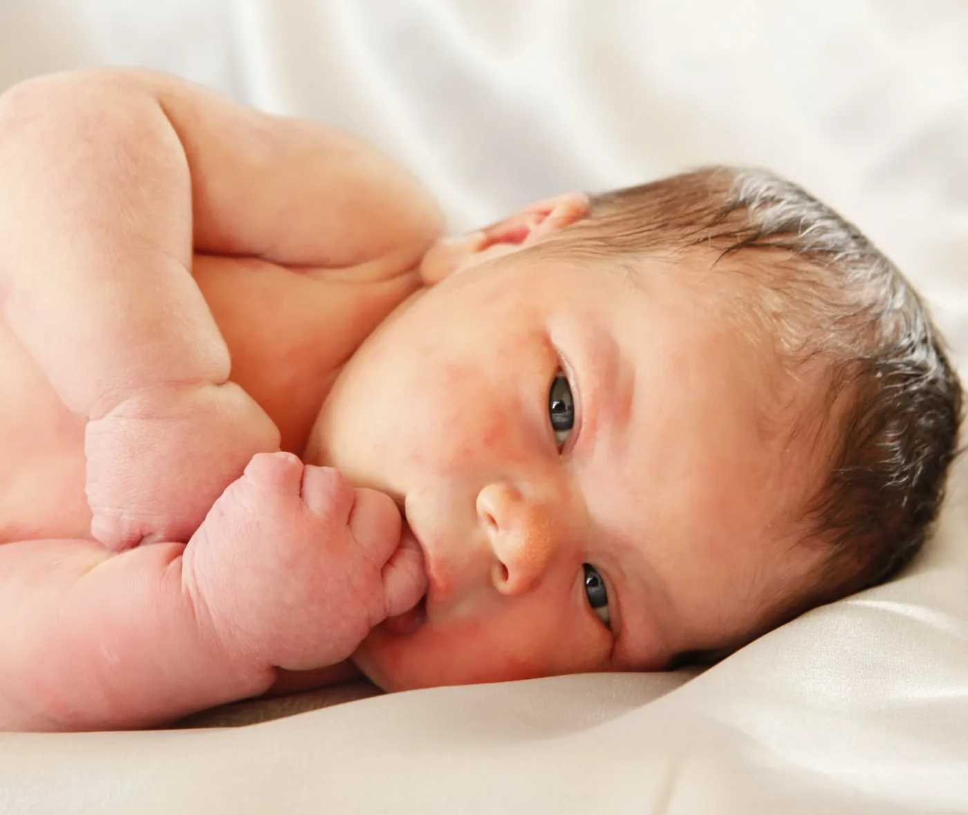 pasgeboren baby ligt op zij met vingertje in zijn mond door fotograaf Alex de Smit