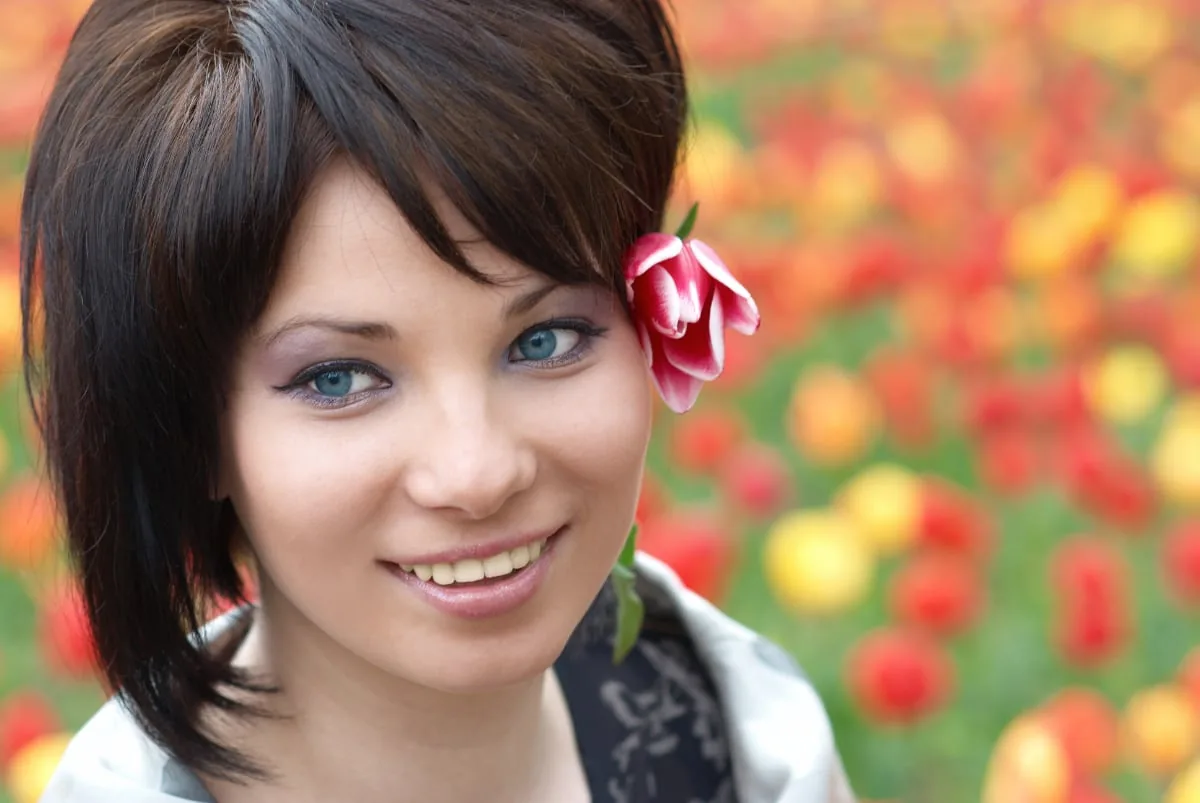 portret van meisje buiten met tulp in haren en tulpen vaag op achtergrond