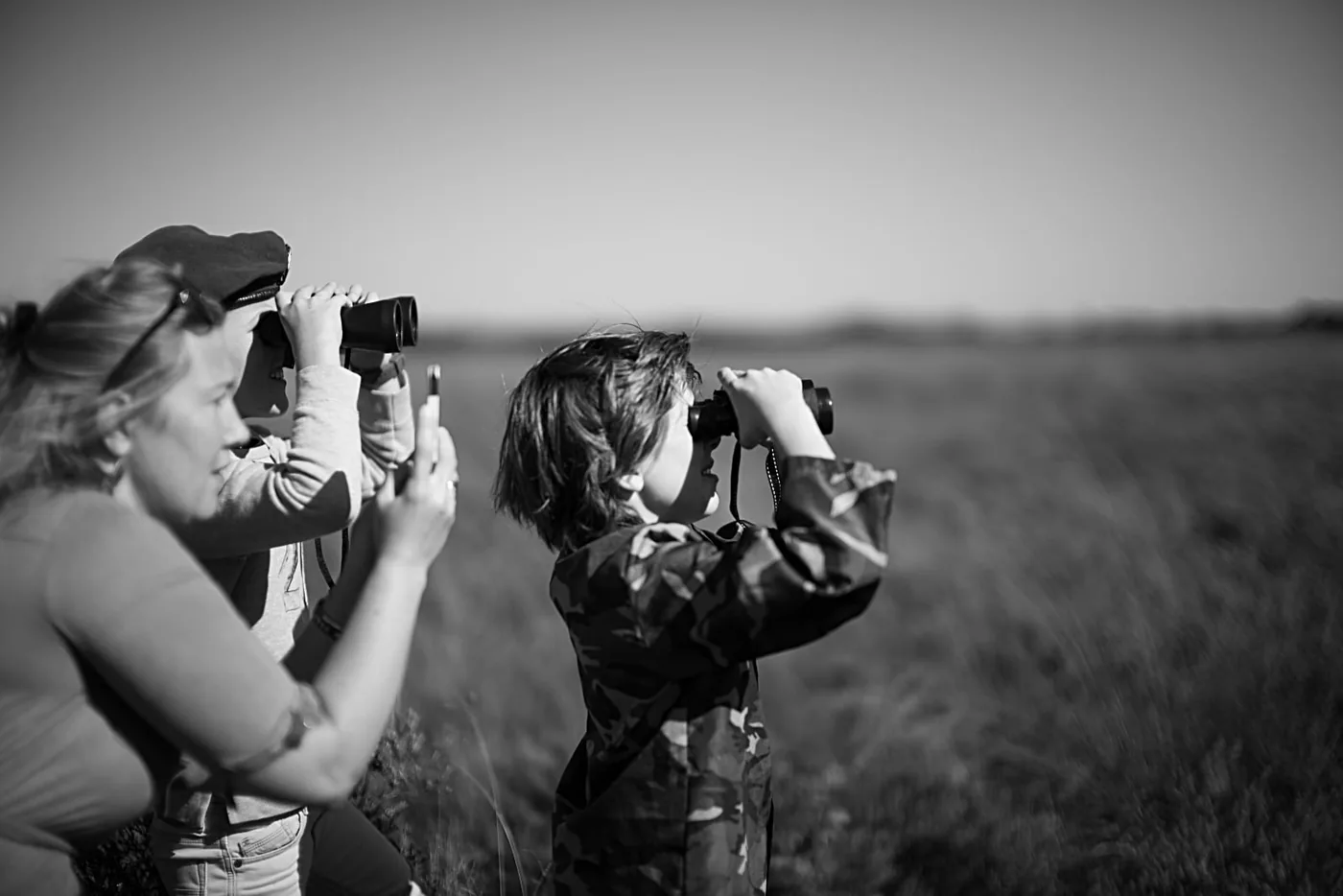 75 Jaar Vrijheid in Beeld — © Sacha de Boer — Airborne landings commemoration on the Ginkel Heath, with a woman taking smartphone photos and a man and child using binoculars