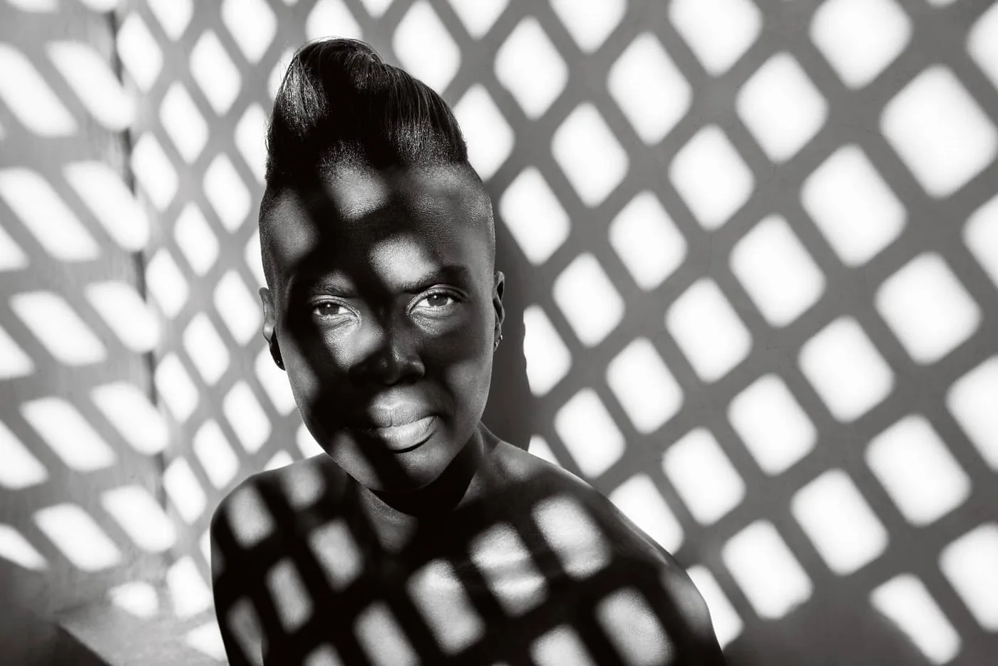 © Annelies Damen - Angalia: portret zwarte vrouw met licht dat door een hekwerk valt