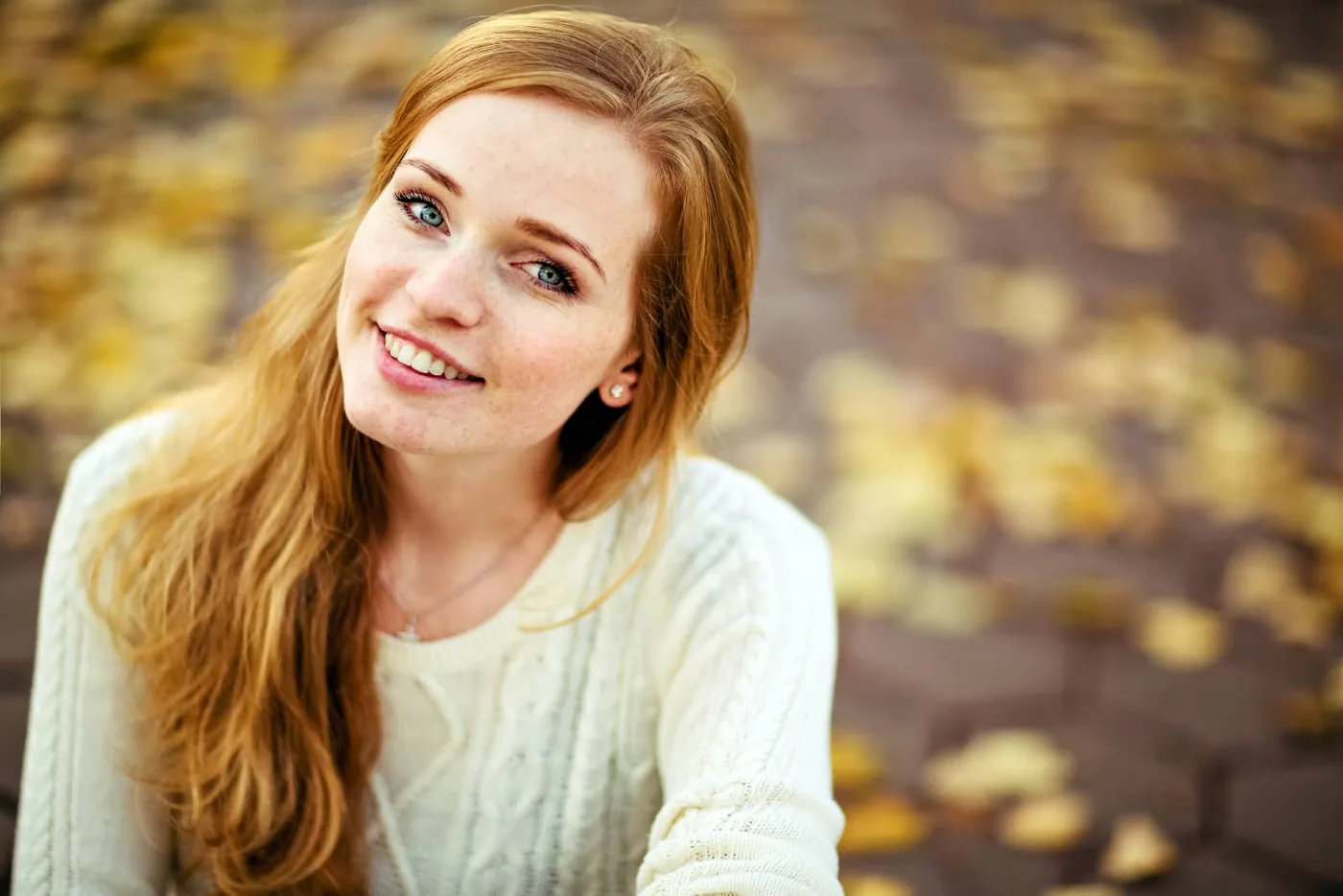 smiling red-haired woman against a blurred autumn background