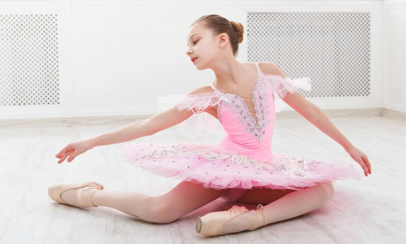 young girl in a pink leotard posing on the floor