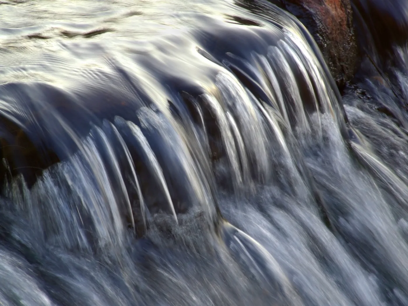 Close-up of flowing water at a waterfall with soft, dreamy motion blur.