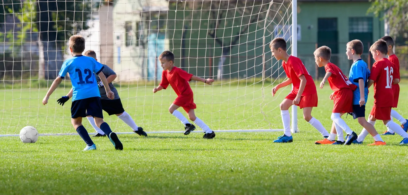 foto van een jong voetbalteam in actie bij doel