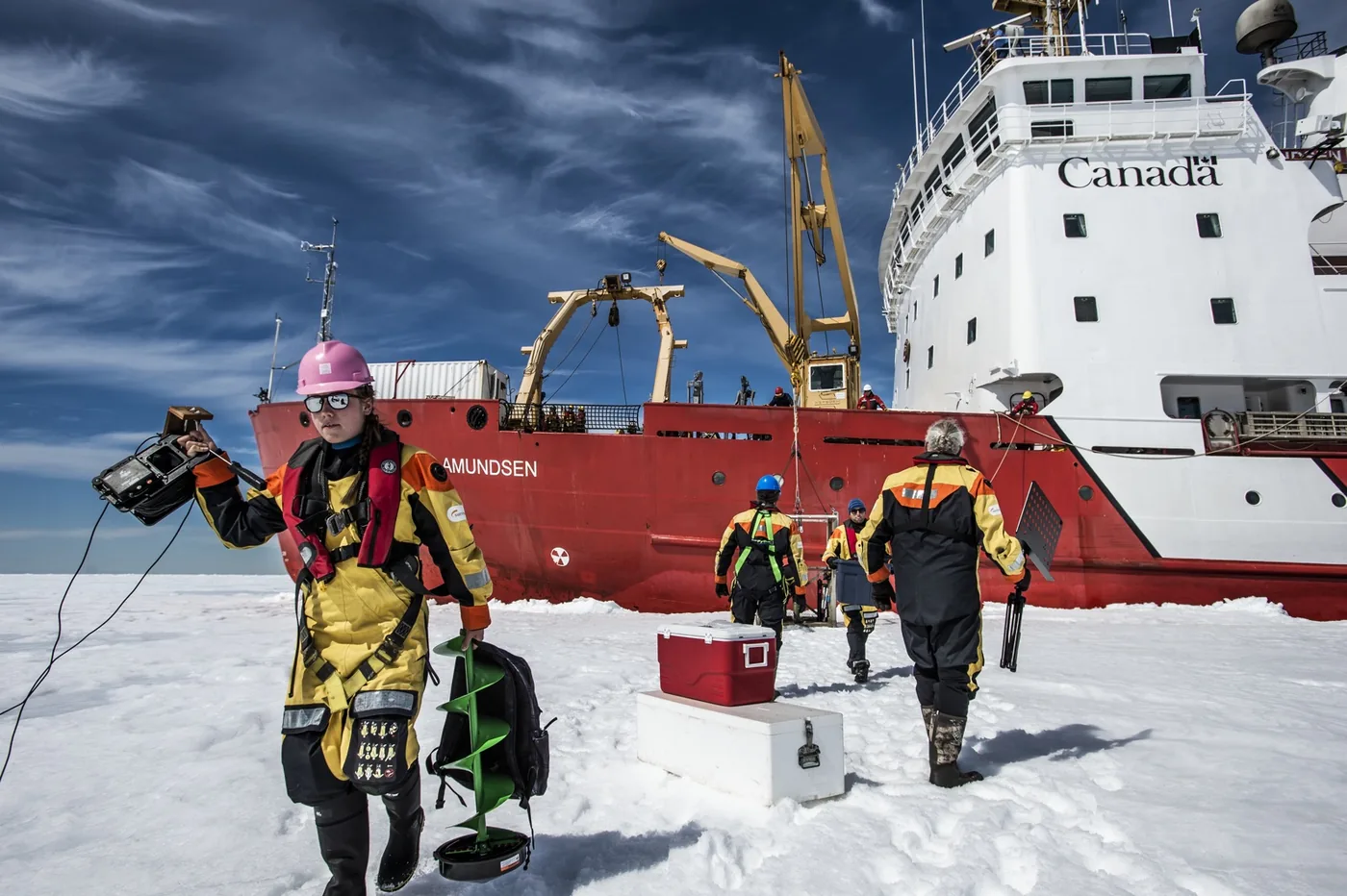 A ship in the Arctic with a camera crew walking in front of it
