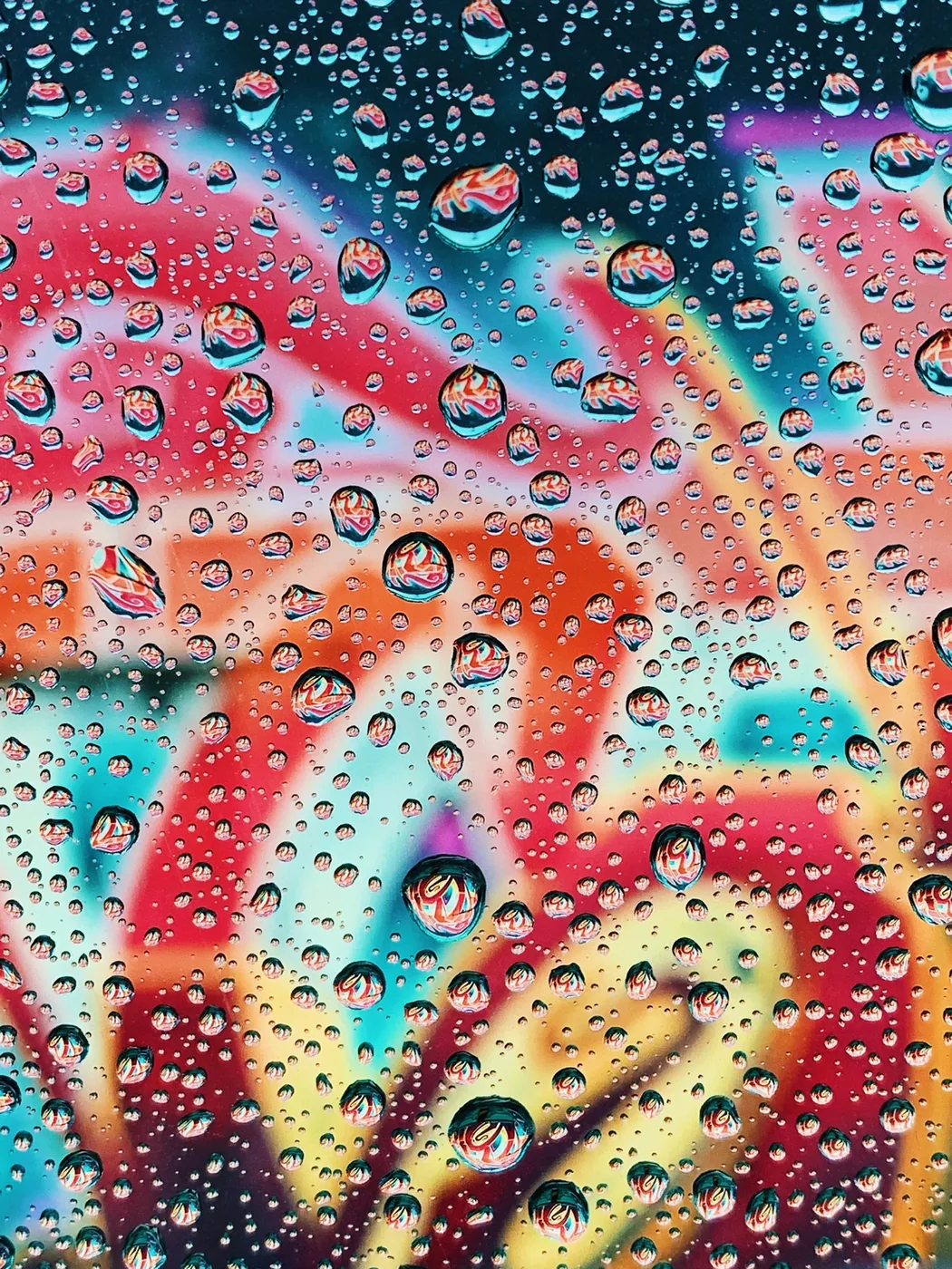Water droplets on a pane of glass with many colors behind them
