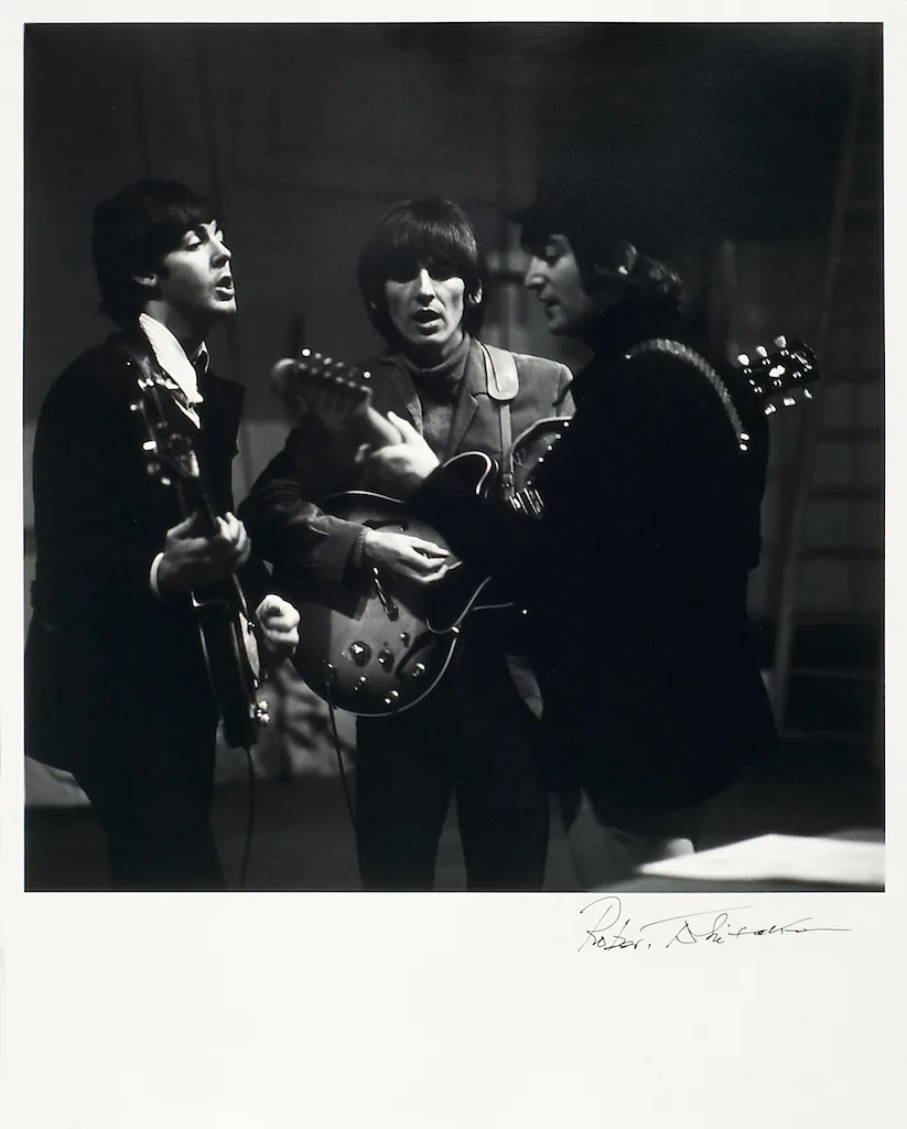 foto van drie van de vier van The Beatles zingend met gitaren