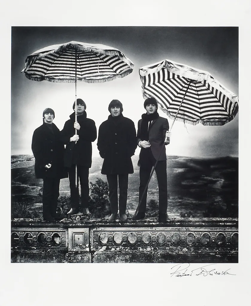 Foto van The Beatles met parasols als paraplu's dragend