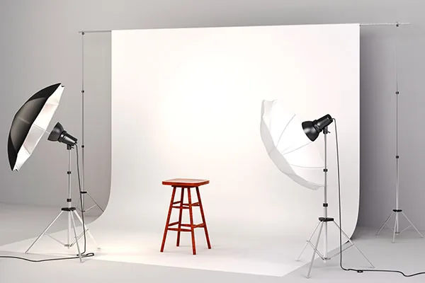 fotostudio met barkruk in set en witte achtergrond en twee paraplu's op flitslampen