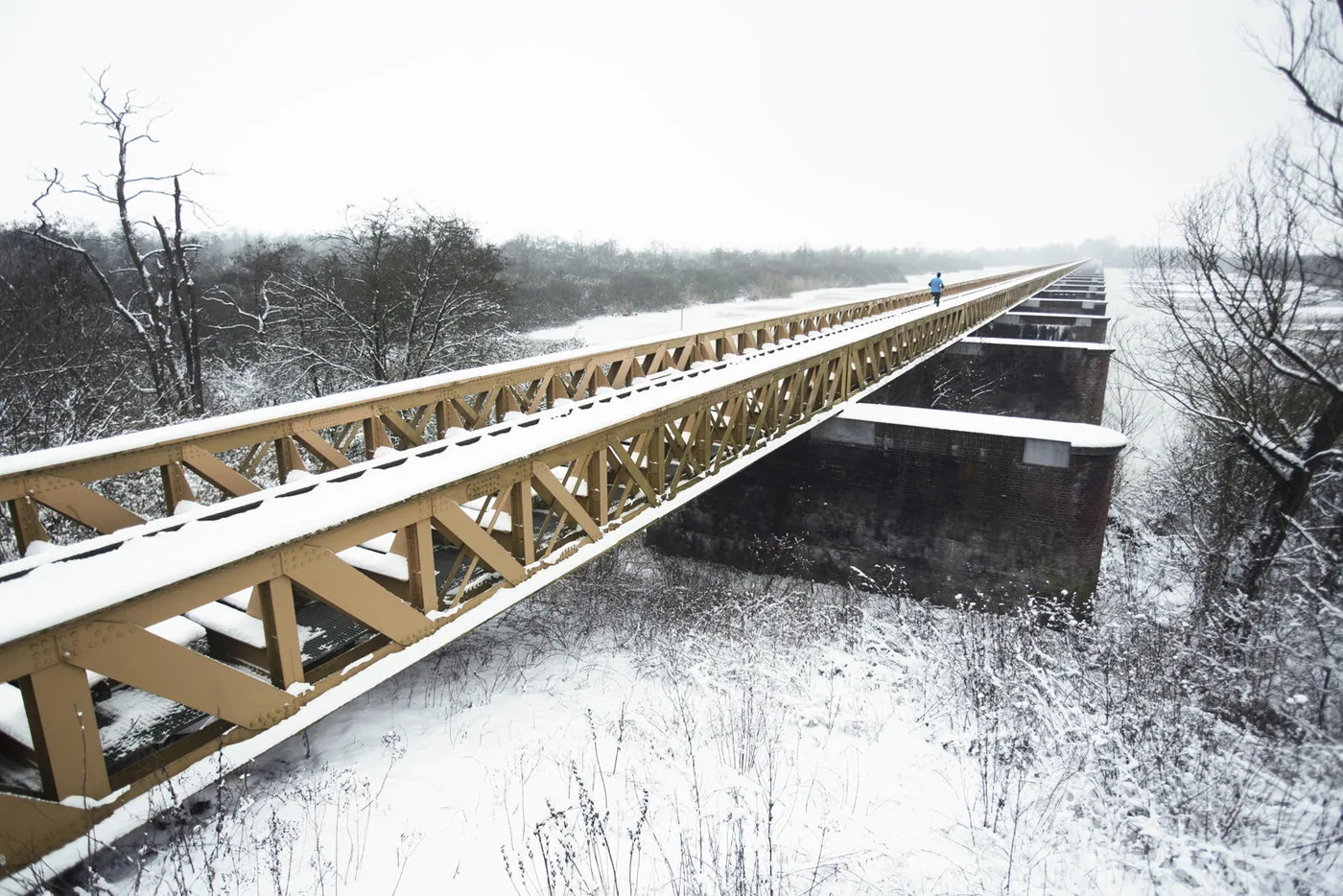 Hardlopers passeren een spoorbrug tijdens een wedstrijd, vastgelegd door Bastiaan Heus.