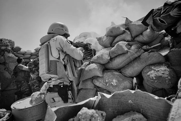 foto: Winnaar Zilveren Camera 2015: Eddy van Wessel | man met geweer achter blokkade me zandzakken in Sinjar