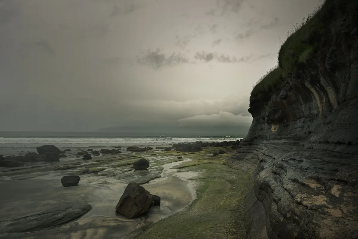 foto van kust met rotsen en grijze wolken