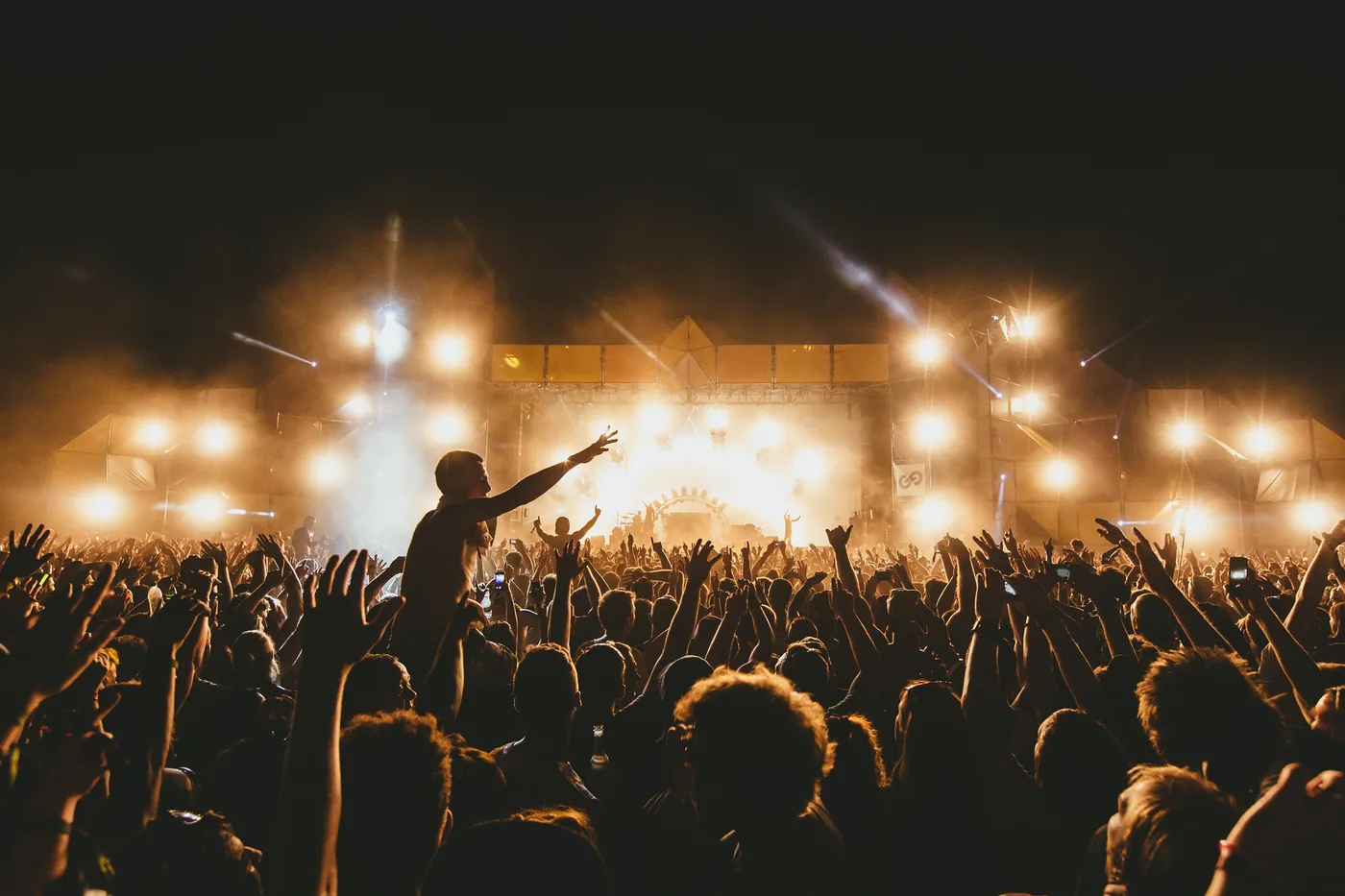 ‍foto: © Paul Underhill van publiek met handen in lucht bij podium festival in nacht