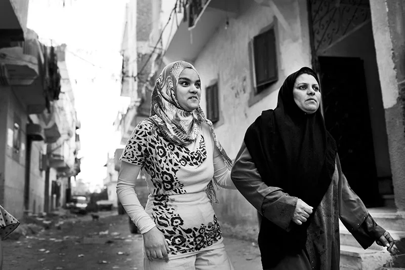 foto: Ahmed Hayman, Egypt, twee vrouwen met hoofddoek in steeg gearmd lopend, de ene is de dochter die blind is en houdt de moeder vast