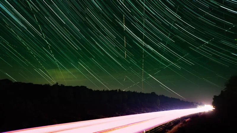 startrailfoto van weg met autolichten en in de lucht de strepen