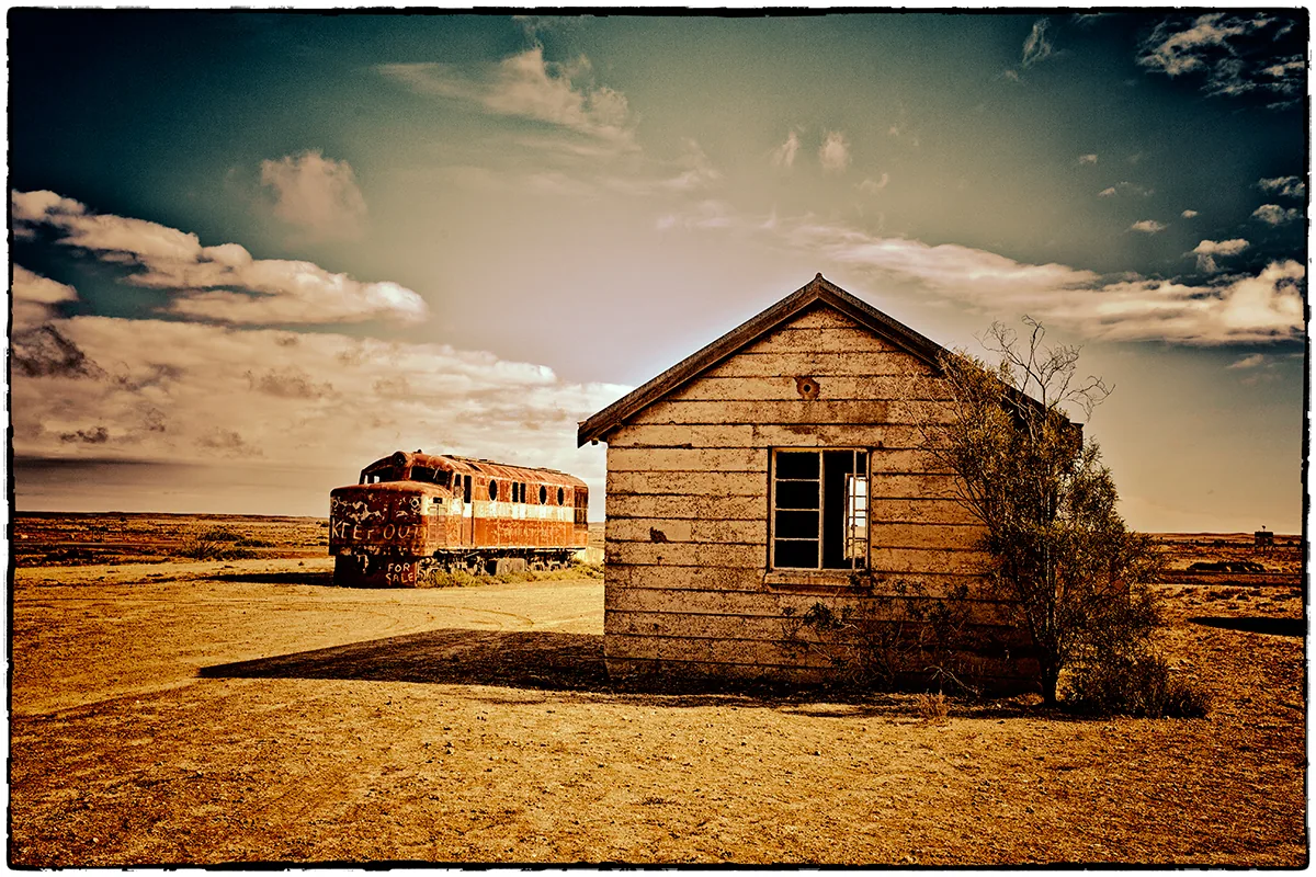 foto van een houten schuurtje en een oude stoomtrein in Australië in leeg landschap