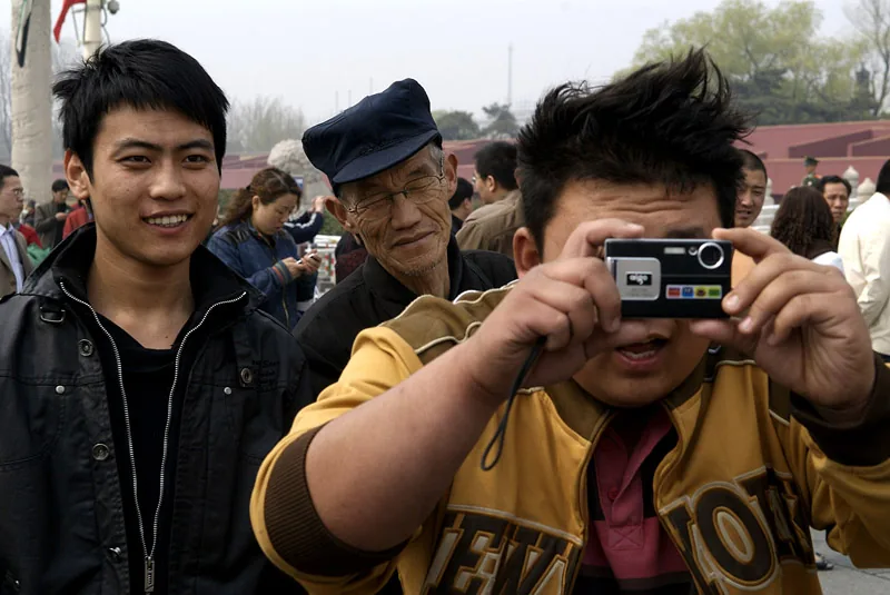 Man takes photos with a compact camera on a busy street in Beijing