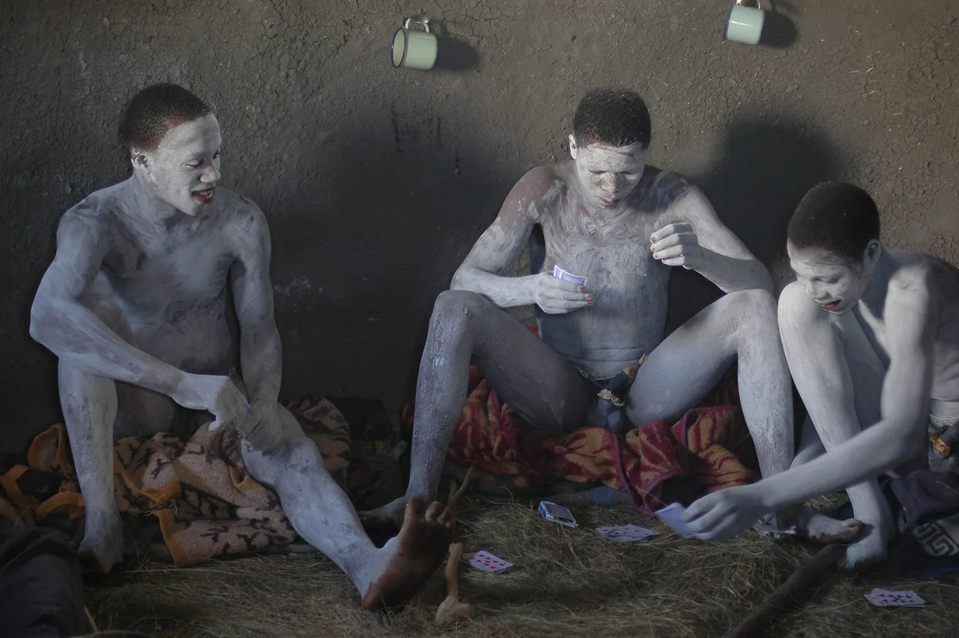Fotografie Zuid-Afrika - Wild Coast, zwarte mannen wit geschminkt spelen kaart in hut op de grond zittend