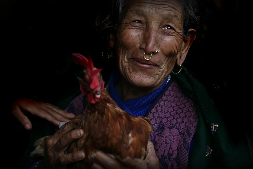 foto van een vrouw met een ring door haar neus en een kip in haar handen