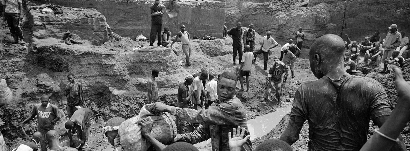 Photograph of workers in Rwanda’s diamond trade carrying shovels and sacks in a mountainous landscape