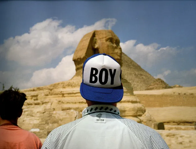 Photo of Martin Parr—a man wearing a cap with the word 'boy'—at the Egyptian Sphinx