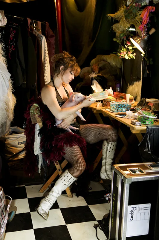 Ellen ten Damme feeds a piglet in a backstage theater setting, photographed by Kees Tabak