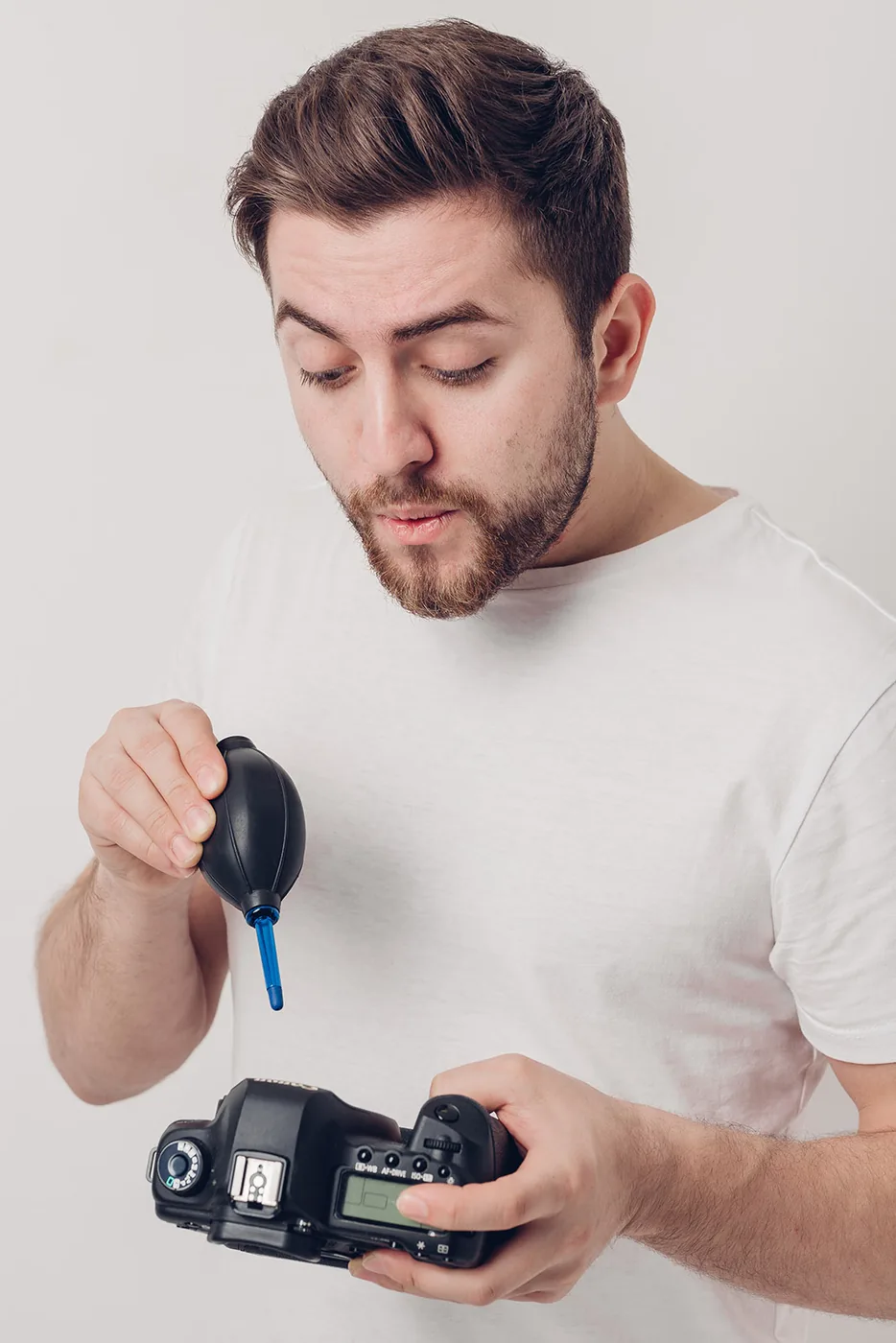 Man cleaning a camera with an air blower