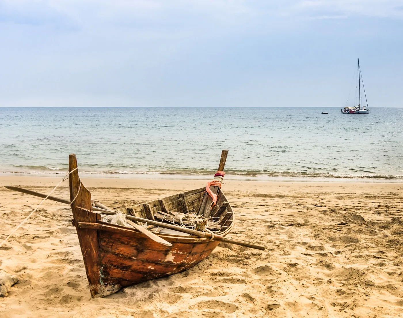 rowing boat on the beach and a sailing boat at sea