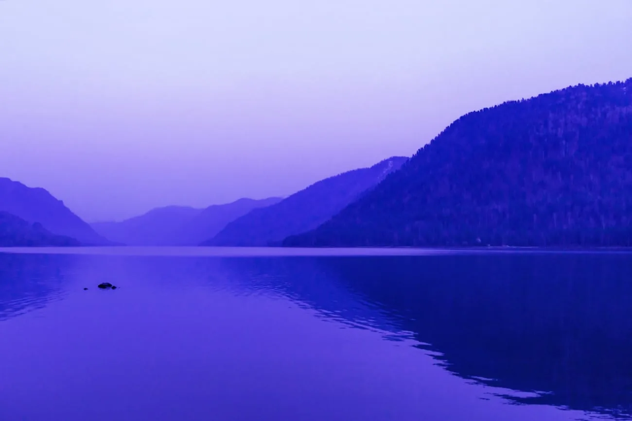 Purple-blue mountain landscape reflected in a calm lake