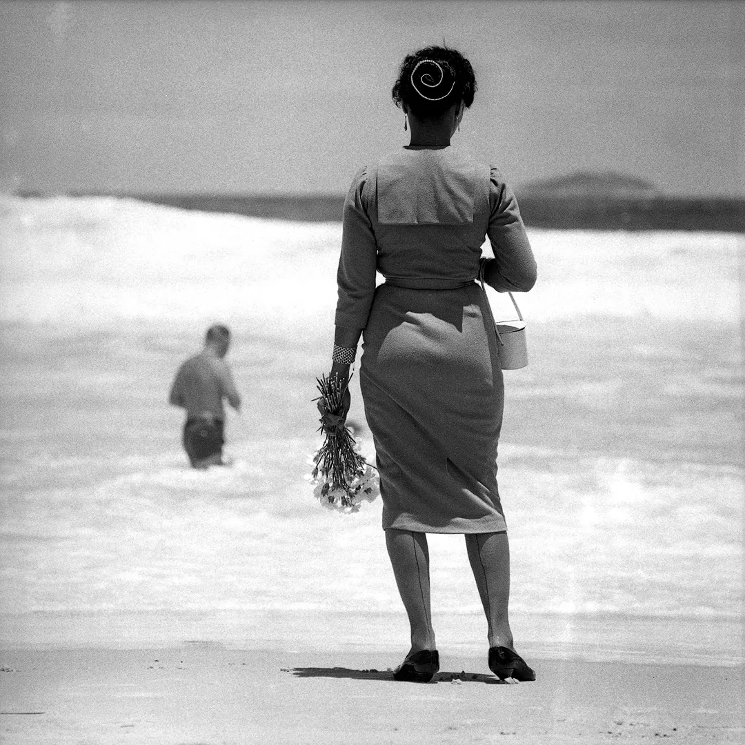 Vrouw met bloemen kijkt uit over Copacabana Beach in Brazilië, gefotografeerd door Rolf Blomberg in 1952