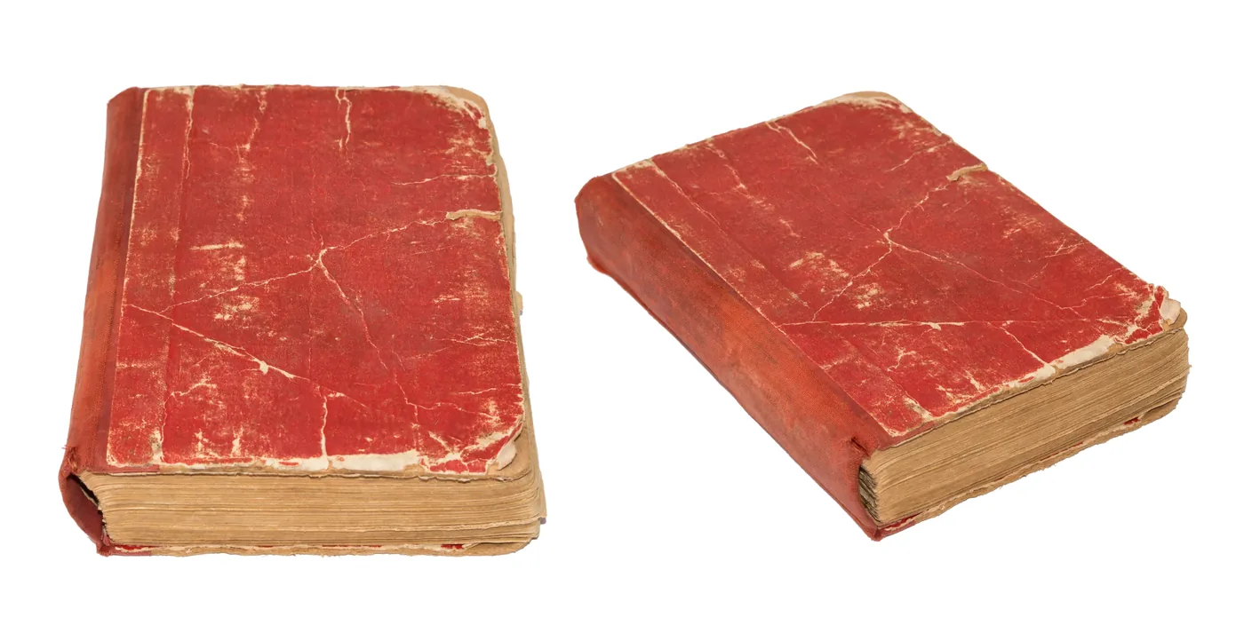 Old worn book with a damaged red cover