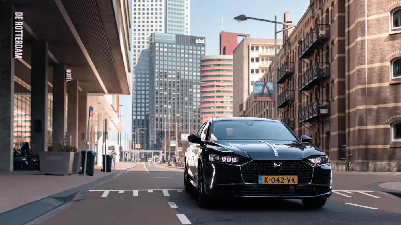 Zwarte auto op een straat tussen moderne en historische gebouwen in Rotterdam
