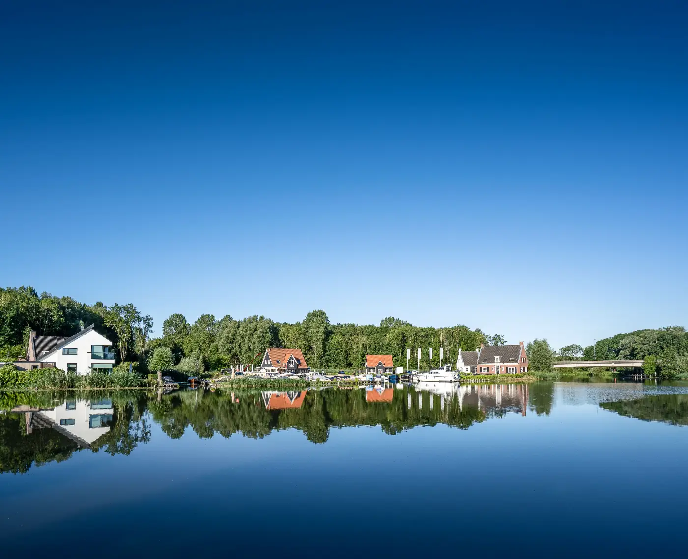 Houses beside the water beneath a blue sky, photographed using a polarizing filter