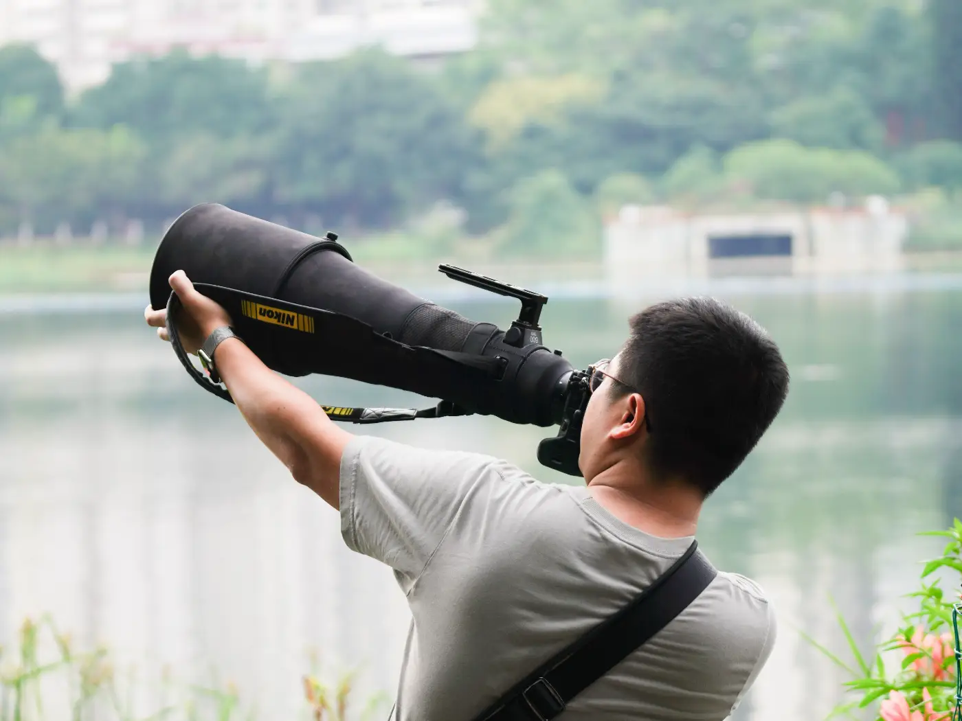 Fotograaf richt een groot Nikon-superteleobjectief uit de hand op een onderwerp