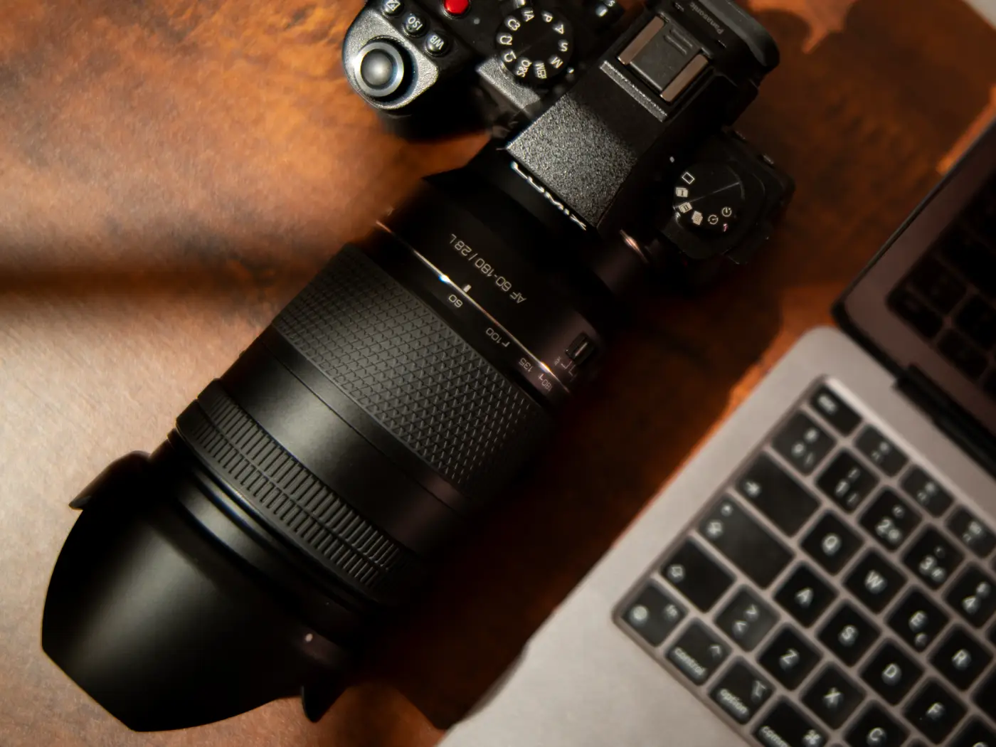 Samyang AF 60-180mm F2.8 on a table beside a laptop