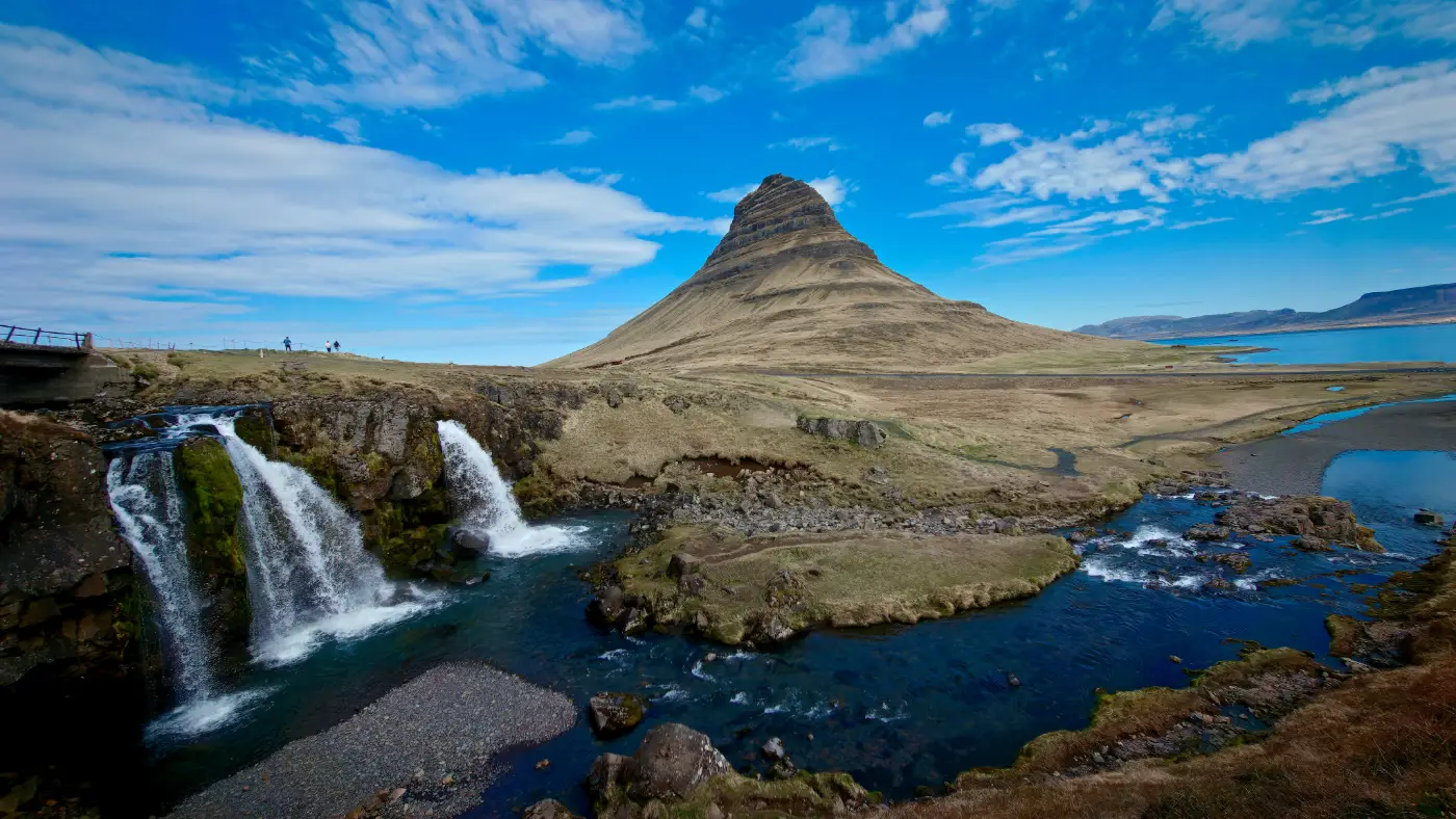 Kirkjufell en de watervallen van Kirkjufellsfoss onder een blauwe lucht in IJsland