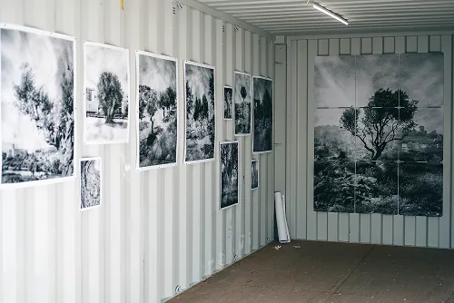 Zwart-witfoto’s van bomen en landschappen hangen aan de wanden van een tentoonstellingscontainer bij Rotterdam Photo.