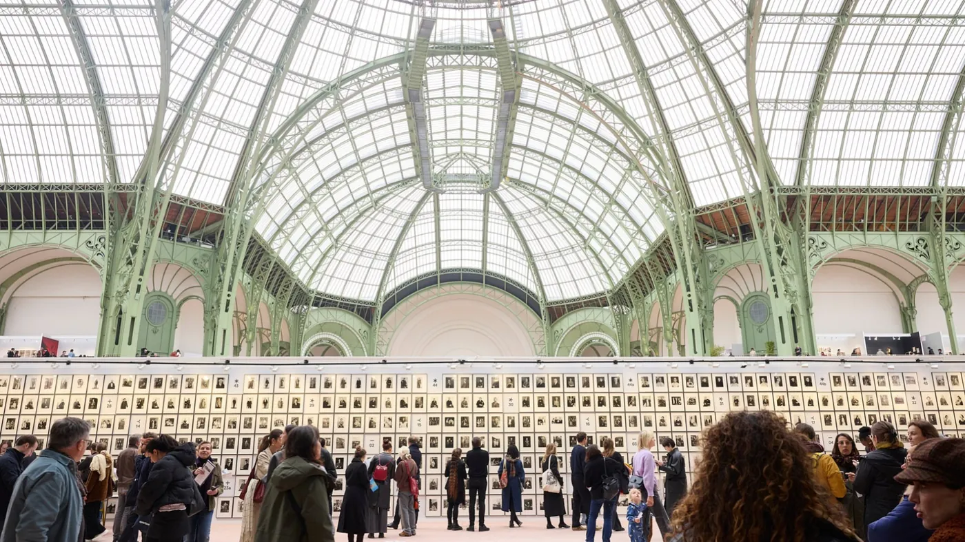 Visitors view a wall of photographic portraits during an earlier edition of Paris Photo beneath the glass roof of the Grand Palais.