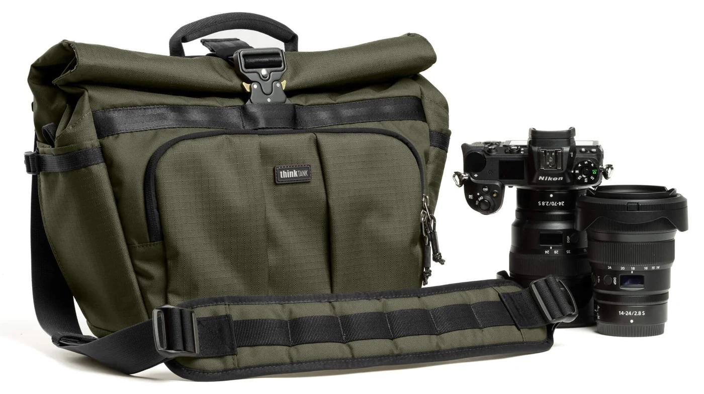 Groene Think Tank FocusPoint Crossbody 13L met gevoerde schouderband, naast een Nikon-camera en objectieven.