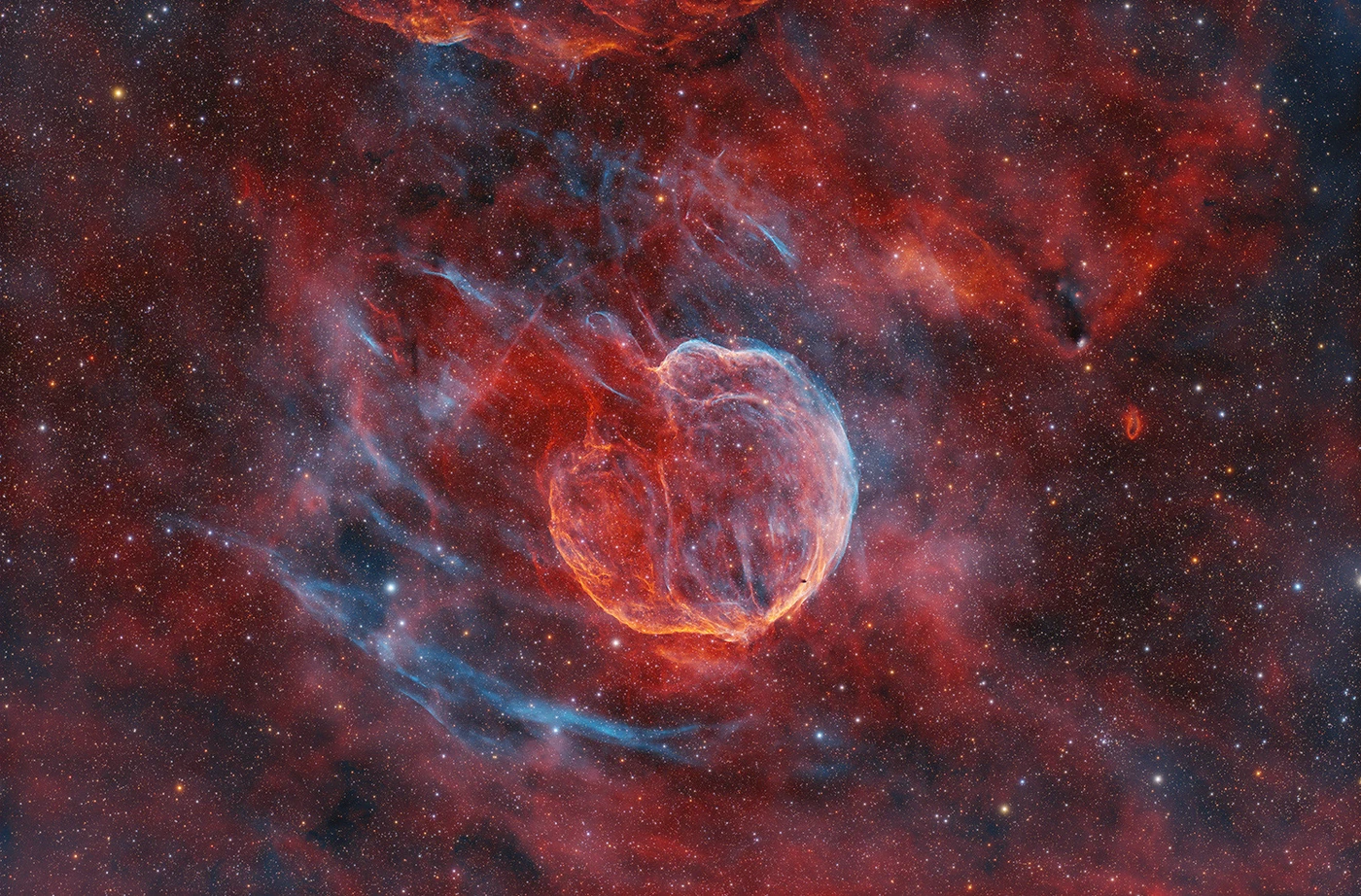 Rode en blauwe gasdraden vormen een opengebroken schil in het sterrenveld rond supernovarest Abell 85.